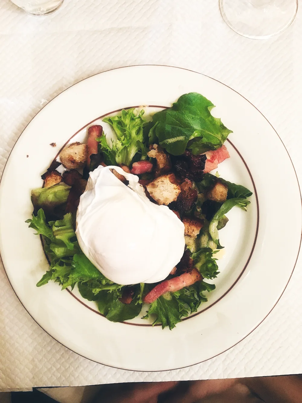 Salade lyonnaise servie Chez Mounier avec œuf poché et lardons croustillants