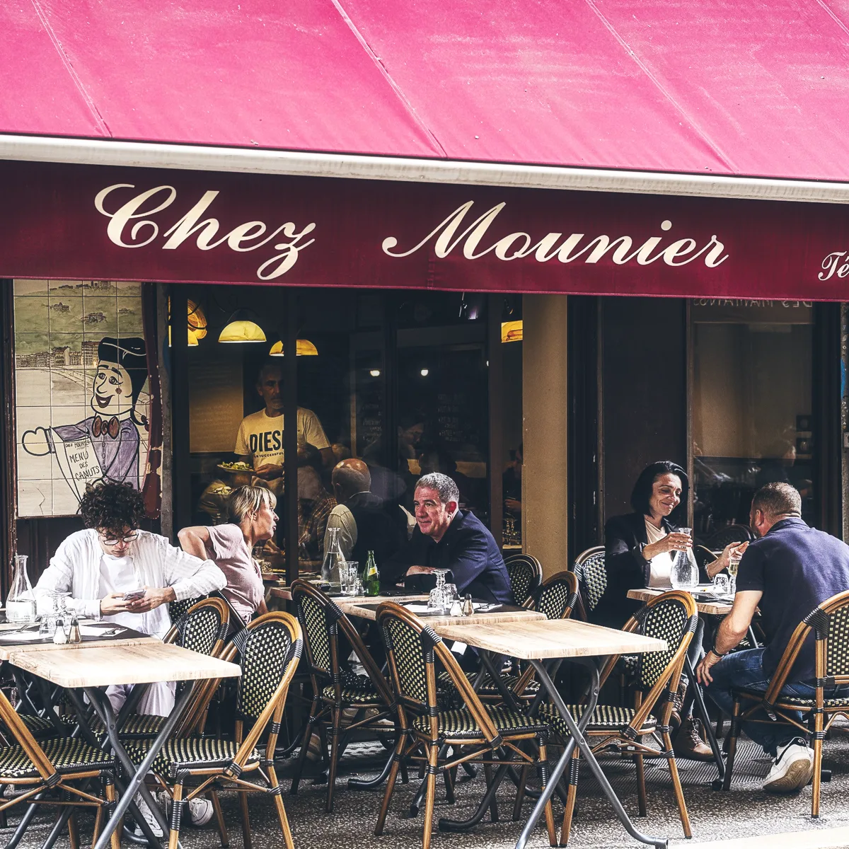 Terrasse du restaurant Chez Mounier avec l'enseigne bordeaux et les clients attablés, Rue des Marronniers à Lyon